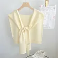 Détail d'un châle en tricot crème avec un nœud élégant présenté sur un cintre en bois - 46x115cm / Blanc Cassé
