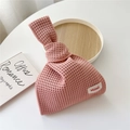 Detail der rosa hohl gestrickten Tasche mit Hildi Webetikett auf weißem Tisch - Hellrosa