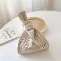 Detail of beige knit knot bag with hollow mesh texture and woven brand label - Beige