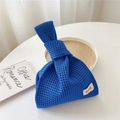 Close-up of blue knit tote bag with mesh hollow design and white logo label tag - Dark Blue