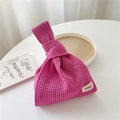 Detail of hot pink knit handbag showing mesh texture and woven brand label on white table - Deep Pink