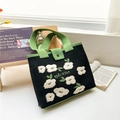 Detail of floral knit tote bag showing thick texture, button flap and 'Nice day' text - Black