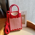 Close-up of red and white wave knit mini handbag on leather seat with long strap - Red & Beige Wave