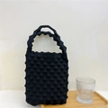 Detail of black knitted handbag featuring 3D bubble texture and wavy handle design - Black