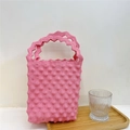Detail of pink knitted bubble texture tote bag with wavy handle on a wooden tray - Pink