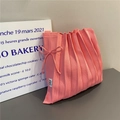 Detailed macro view of pink pleated knit bag with delicate side ribbon bow detail - Pink