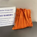 Close-up of orange knitted tote bag featuring a pleated design and decorative drawstring bow - Orange