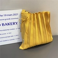 Macro shot of bright yellow knitted tote bag with pleated texture and bow detail - Yellow