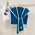 Dettaglio scialle in maglia blu scuro con bordo bianco a contrasto su gruccia in legno - Blu Chiaro