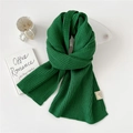 Forest green ribbed knit scarf with woven fabric label on minimalist white surface - Green