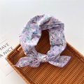 Dettaglio di un foulard a fiori viola annodato a fiocco su un vassoio di vimini marrone - 58cm / 26 Thunbergia Viola