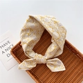 Detail view of a yellow floral cotton hair tie with a knot, placed on a woven tray - Bamboo Floral Yellow (25)
