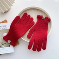 Detail of red ribbed knit gloves with decorative brand label on warm wooden tray - Red (Ruffle Cuff)