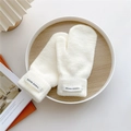 Detail of white knitted mittens with Hand Made label on rustic wooden surface - One Size / Cream