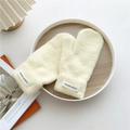 Close-up of beige thick knit mittens with a stitched Hand Made label on the cuff - One Size / Beige