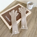 Detalle de guantes de punto acanalado color avena con parche de marca y función táctil - Sin Dedos con Tapa / Beige