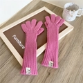 Detalle de guantes largos de punto rosa fucsia con textura acanalada y etiqueta de marca - Estilo de cinco dedos / rosa intenso