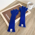 Close-up of royal blue knitted long gloves with white woven label and five-finger design - Five-Finger Style / Sapphire Blue