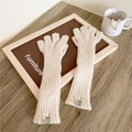 Detailed texture of cream knitted long arm warmers with a stylish label on a wooden desk - Five-Finger Style / Cream