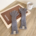 Close-up of grey knit arm warmers with ribbed texture and white brand label detail - Fingerless Style / Medium Grey