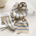Detail of blue striped knit scarf with leather label and ribbed hem on white table - Blue & Beige Stripes