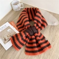 Sciarpa corta in maglia a righe arancioni e nere con logo in pelle su tavolo in legno - Righe Arancione e Nero
