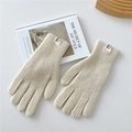 Detailed close-up of cream knit gloves with ribbed texture on a wooden tray - Cream