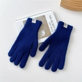 Close-up of royal blue knitted gloves with ribbed cuffs and branded label on art book - Dark Blue