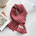Red and white houndstooth knit scarf with logo label on a minimalist background - Red