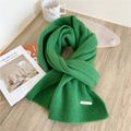 Bright green knitted wool scarf with vertical texture and metal brand tag on wood table - Grass Green