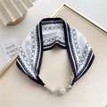 Detail of black and white silk scarf featuring geometric patterns and diamond-studded metal clasp - Black and White Rippled Grid
