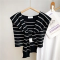 Détail du châle en maille rayée noir et blanc avec nœud décoratif et étiquette de marque - Doubles Rayures Noir