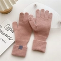 Detail of pink knitted gloves with ribbed cuffs and material label on white background - One Size / Lotus root pink