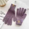 Detail der Waffelstruktur und Lederetikett an lavendelfarbenen Strickhandschuhen - Lila