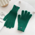 Detailansicht der Strickstruktur und des Materialetiketts der dunkelgrünen Handschuhe - Dunkelgrün