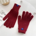 Detailed close-up of dark red chunky knit gloves with ribbed cuffs on white surface - Burgundy