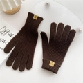 Detailed view of dark brown knitted gloves with ribbed cuffs and material tag detail - Brown
