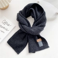 Close-up of dark grey knitted scarf with textured ribbing and brown leather brand label - Black and Gray