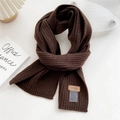 Close-up of coffee brown ribbed knit scarf featuring a leather brand label and care tag - Brown