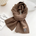 Detail of dark brown ribbed knit scarf showing texture with brand leather patch - Dark Coffee