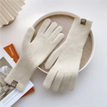 Detailed close-up of beige knitted gloves featuring vertical ribbed texture and leather logo label - One Size / Beige