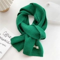 Detail view of emerald green knitted scarf featuring handmade label and ribbed texture - 22x180cm / Dark Green