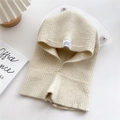 Beige knitted balaclava hood with ribbed texture and white label on a cozy background - Beige