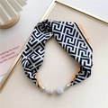 Detail showing the Greek key pattern silk scarf with sparkling rhinestone spheres - Black White Orange Edge Maze