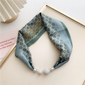 Close-up of a floral silk scarf featuring magnetic metal clasps and rhinestone pendants - Grey Green Cross Floral