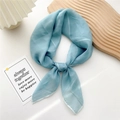 Elegant light blue silk square scarf styled with a knot on a decorative tray - Cyan