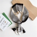 Elegant black and white striped silk scarf with gold accents tied on a wooden display - Black Beige Stripes