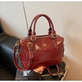 Dettaglio macro della borsa Boston in pelle bordeaux con cuciture bianche e finiture oro - Borgogna