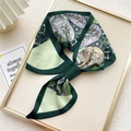 Elegant dark green paisley printed silk scarf tied in a bow on a display board - Four-leaf Heart Green (10F)