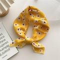 Foulard quadrato giallo con stampa a margherite annodato a fiocco su tavolo bianco - Piccola Margherita Gialla